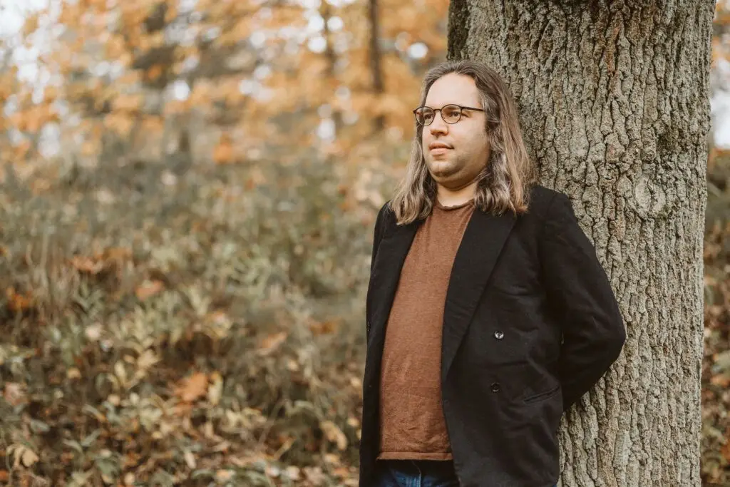 Andreas Hunkeler lehnt sich an einem Baum, Symbol für Wurzeln und Wachstum